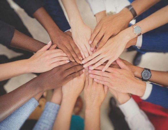 Diverse hands stacked together in a circle, symbolizing teamwork and unity.