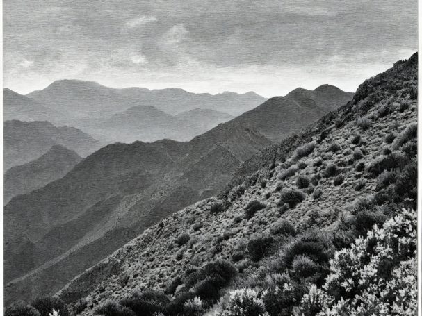 Black and white landscape of rolling mountain ranges and distant peaks.